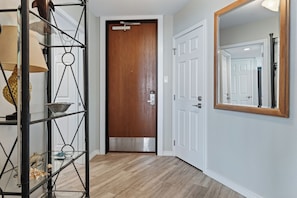 A hallway with a wooden door, a white door, and a mirror on the wall. - Sandpiper 1005: Oceanfront 3BR condo with pool, hot tub, and beach access in Port Aransas. (Port Aransas)