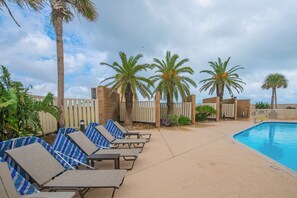 Ein Poolbereich mit Liegestühlen, Palmen und einem Schwimmbecken.