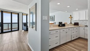 A modern kitchen with white cabinets, a wooden countertop, and a view to the outside. - Sandpiper 1005: Oceanfront 3BR condo with pool, hot tub, and beach access in Port Aransas. (Port Aransas)