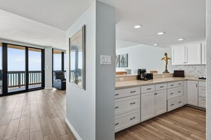 Eine moderne Küche mit weißen Schränken, einer Holz Arbeitsplatte und Blick ins Freie.