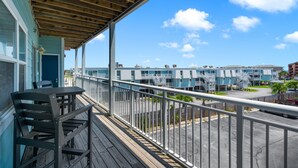 En balkon med udsigt over kystlandskabet, med træterrasse og gelænder i metal.
