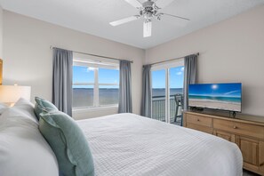Ein Hotelzimmer mit Bett, Fernseher, Deckenventilator und Meerblick.
