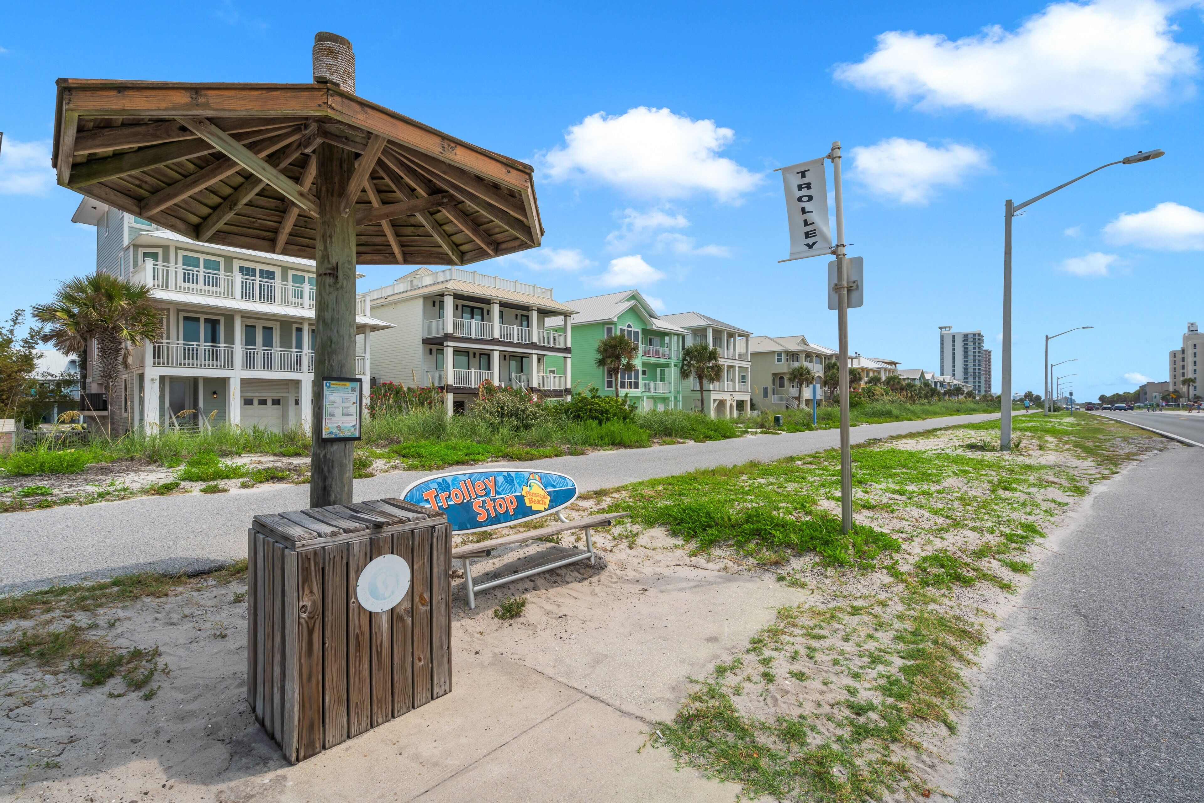 A coastal street with beach houses, a trolley stop sign, and a wooden structure.