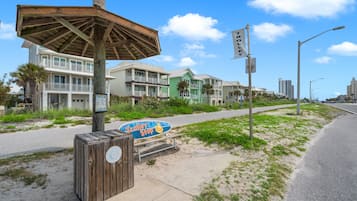 A coastal street with beach houses, a trolley stop sign, and a wooden structure.
