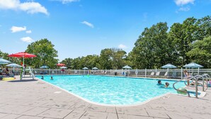 A swimming pool with a tiled deck, umbrellas, and a white fence. - Casa de Cozy - Resort Condo Minutes from Branson & Lake Taneycomo (Branson)