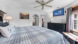 A bedroom with a bed, a ceiling fan, a TV, a dresser, a window with curtains, and a painting on the wall. - Casa de Cozy - Resort Condo Minutes from Branson & Lake Taneycomo (Branson)