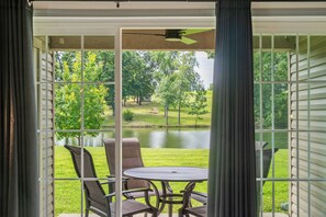 A patio with a table and chairs, a view of a lake, and a grassy area with trees. - Casa de Cozy - Resort Condo Minutes from Branson & Lake Taneycomo (Branson)