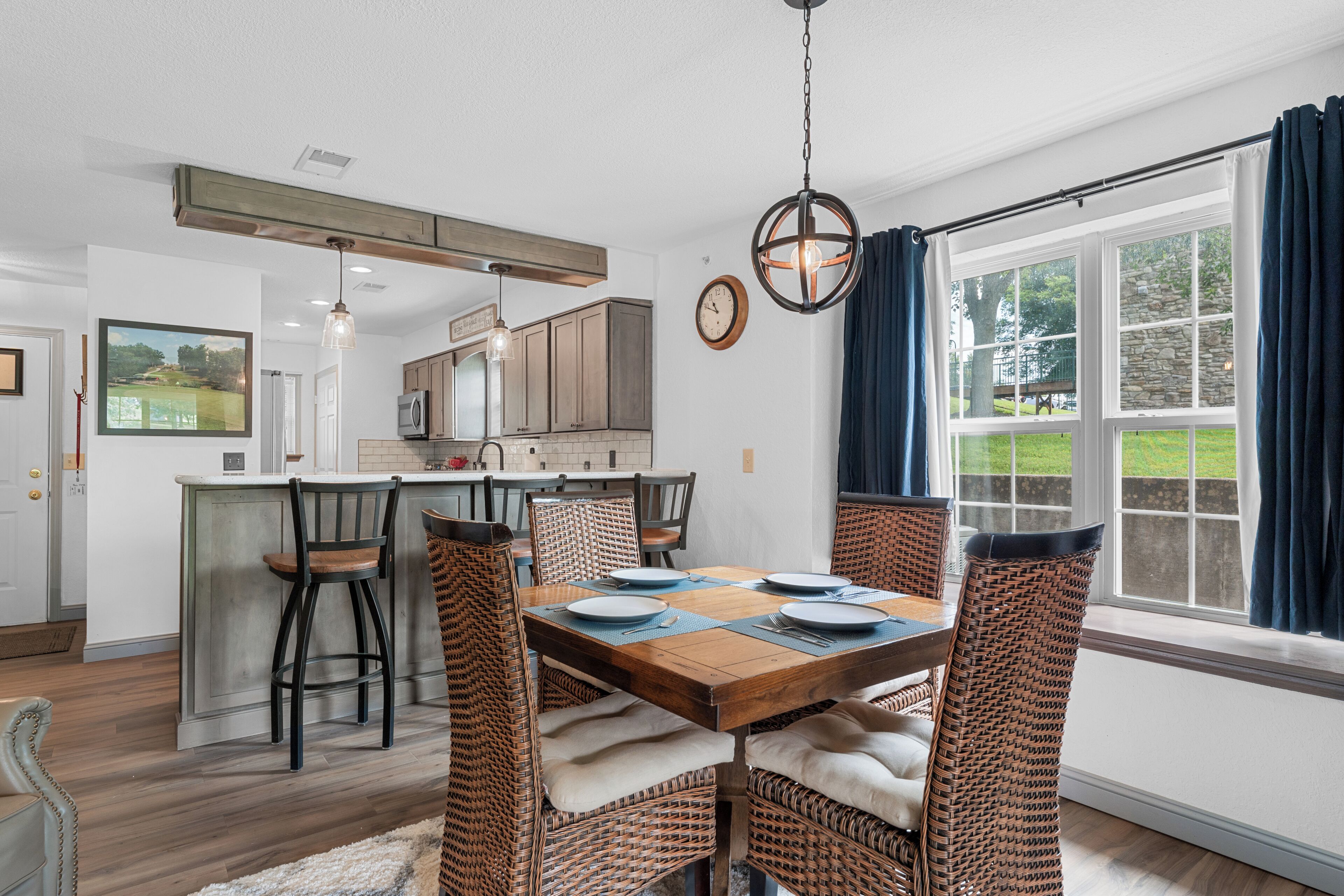 A dining area with a wooden table, wicker chairs, and a view of the outdoors.