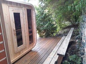 Um deck de madeira com um banco e uma estrutura de madeira com portas de vidro.