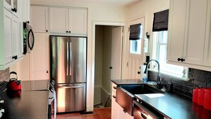 Una cocina moderna con gabinetes blancos, electrodomésticos de acero inoxidable y una encimera negra.