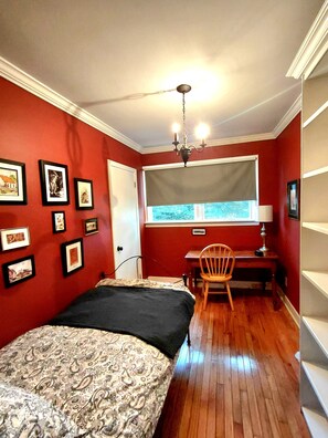 Een slaapkamer met een bed, een bureau, een stoel en een raam met uitzicht.