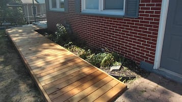 Un immeuble résidentiel avec une façade en briques, une terrasse en bois et un petit jardin.