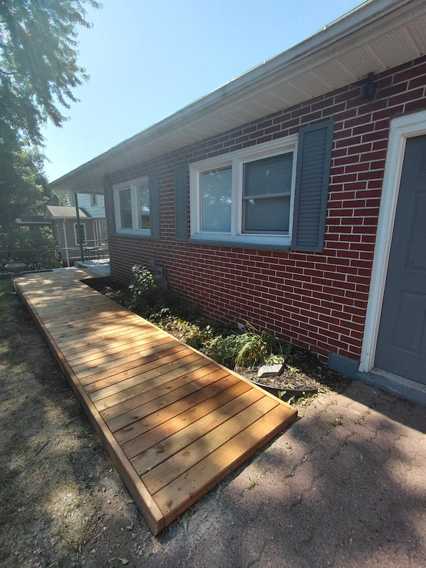 A residential building with a brick exterior, a wooden deck, and a small garden area.