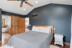 A bedroom with a large bed, wooden wardrobe, ceiling fan, and a nightstand. - Heated Pool, Game Room & Outdoor Living Near Ha Ha Tonka (Camdenton)