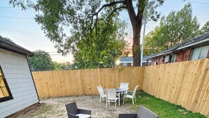 A backyard with artificial grass, a patio table, and two sofas. - The Guernsey Getaway New Construction 3 Bedroom 2 Bathroom (Memphis)