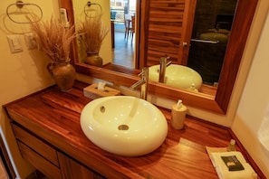 Une salle de bain avec un meuble-lavabo en bois, un grand lavabo blanc, un miroir et un porte-serviettes.