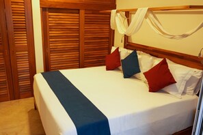 A bed with a white and blue bedspread, red and blue pillows, and a canopy.