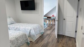 A bedroom with a bed, a TV mounted on the wall, and a wooden floor. - Spacious 5-bedroom house in peaceful Brigantine with AC (Brigantine)