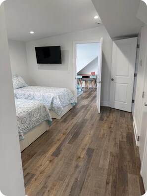 Ein Schlafzimmer mit einem Bett, einem an der Wand montierten Fernseher und Holzboden.