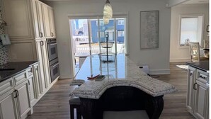 A kitchen with a large island, white cabinetry, and a view to the outside. - Spacious 5-bedroom house in peaceful Brigantine with AC (Brigantine)