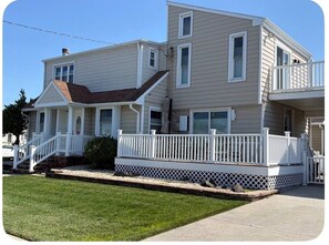 A two-story house with a front porch, a balcony, and a small deck area. - Spacious 5-bedroom house in peaceful Brigantine with AC (Brigantine)