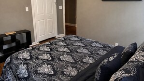 Ein Schlafzimmer mit einem Bett, einer Tür, einem Gemälde und einem Konsolentisch.