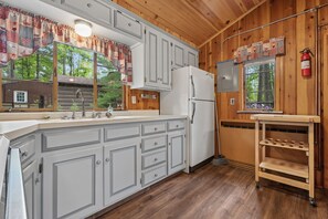 A kitchen with white cabinets, a stainless steel sink, and a white refrigerator.