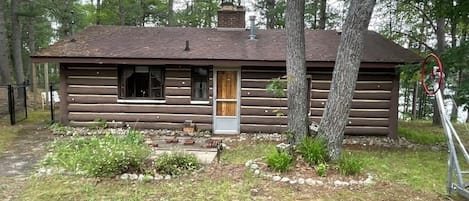 A log cabin with a front door, windows, and a chimney.