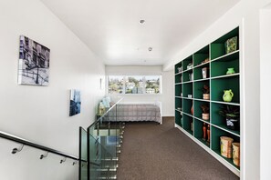 A modern interior with a staircase, a bed, a green shelving unit, and artwork on the walls. - Sea and City Penthouse - Napier CBD (Napier)