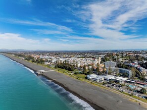 Luchtbeeld van een kustplaats met een strand, gebouwen en een heldere lucht.