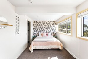 Een slaapkamer met een bed, een raam, een deur en een muur met behang.
