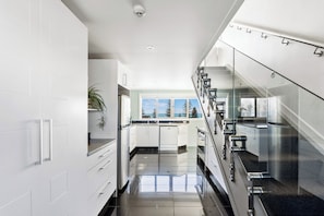 A modern kitchen with white cabinets, a stainless steel range, and a view of the outdoors. - Sea and City Penthouse - Napier CBD (Napier)