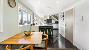 Una cucina moderna con isola centrale, zona pranzo con tavolo e sedie in legno e vista sull'esterno tramite ampie finestre.
