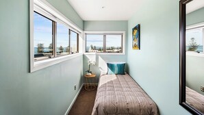 Una camera da letto con un letto, una finestra, un tavolino con una pianta e un quadro appeso al muro.