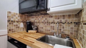A kitchen with a microwave, sink, and tiled backsplash. - Bright Rodeo Retreat | Walk to Everything 246 (River Ranch)