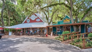 A rustic coffee shop with outdoor seating, a Hershey's ice cream sign, and a ranch-themed building with a green awning. - Bright Rodeo Retreat | Walk to Everything 246 (River Ranch)