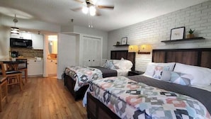 A bedroom with two beds, a desk, and a kitchenette. - Bright Rodeo Retreat | Walk to Everything 246 (River Ranch)