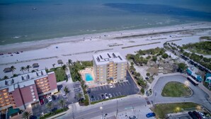 Vue aérienne d’un hôtel situé en bord de mer, avec une piscine, un parking et un accès à la plage.