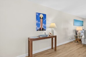 Ein Zimmer mit einem Holzkonsolentisch, einer Lampe, einem Wandbild und einem kleinen Nachttisch ebenfalls mit einer Lampe.