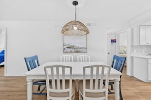 A dining area with a white table and chairs, a woven pendant light, and a framed landscape painting on the wall. - Sugar Sand Beachfront Condo, Spectacular Gulf Views, 24' Lanai, 2BR/2BA, #433 (Fort Myers Beach)