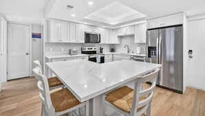 Une cuisine moderne avec des meubles blancs, un îlot central et des appareils électroménagers en acier inoxydable.