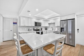 A modern kitchen with white cabinetry, a central island, and stainless steel appliances. - Sugar Sand Beachfront Condo, Spectacular Gulf Views, 24' Lanai, 2BR/2BA, #433 (Fort Myers Beach)