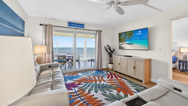 Une chambre d’hôtel avec balcon, ventilateur de plafond, télévision et vue sur l’océan.