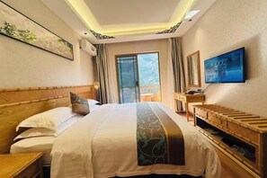 A hotel room with a large bed, a wooden headboard, a television, and a balcony with a view.