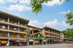 A traditional building with multiple balconies, a central entrance, and outdoor seating areas. - Libo Daqikong Bamboo Garden Boutique Hotel (East Gate Ticket Hall Store of Xiaoqikong Scenic Area) (Libo)