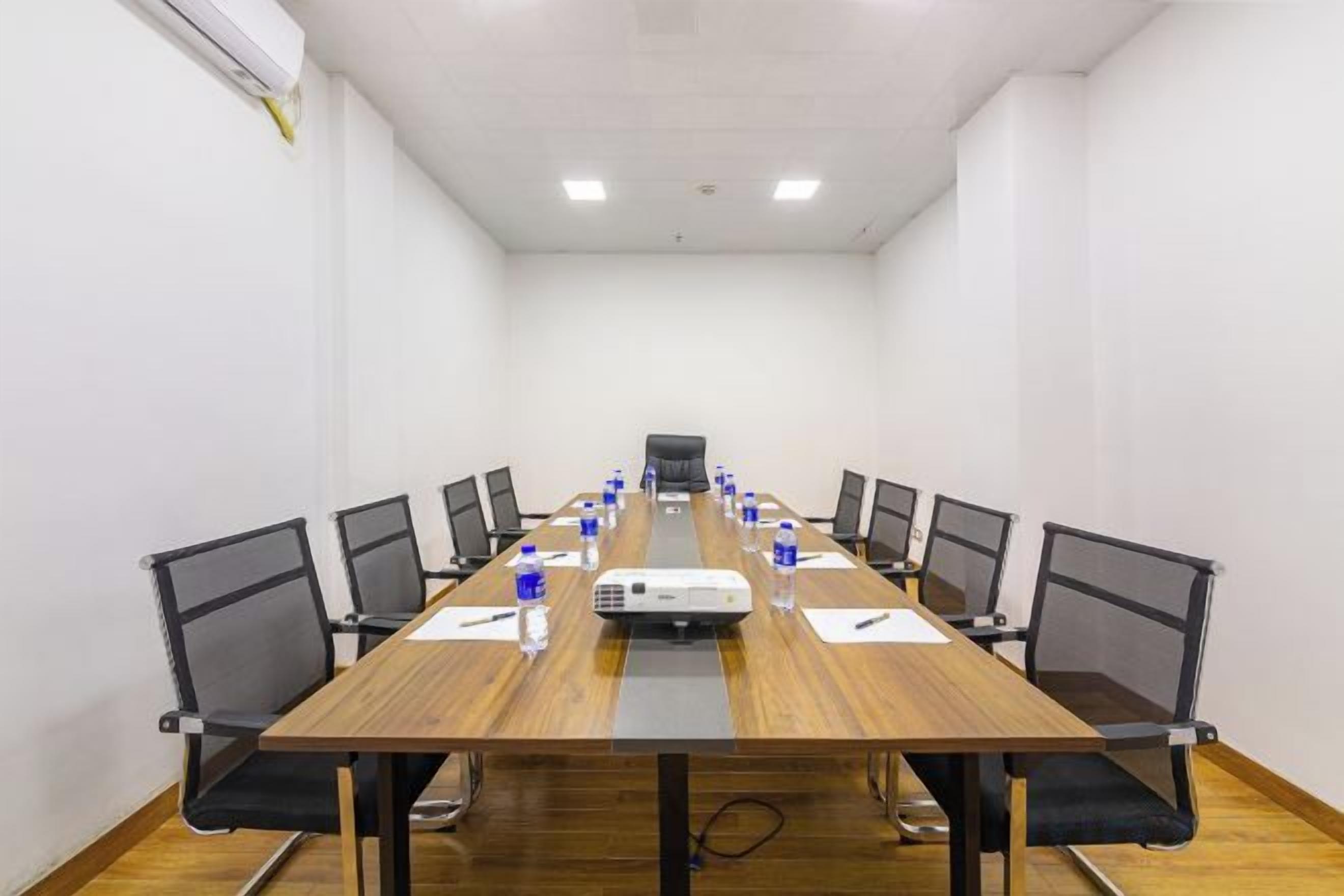 A conference room with a long table, chairs, a projector, and water bottles.