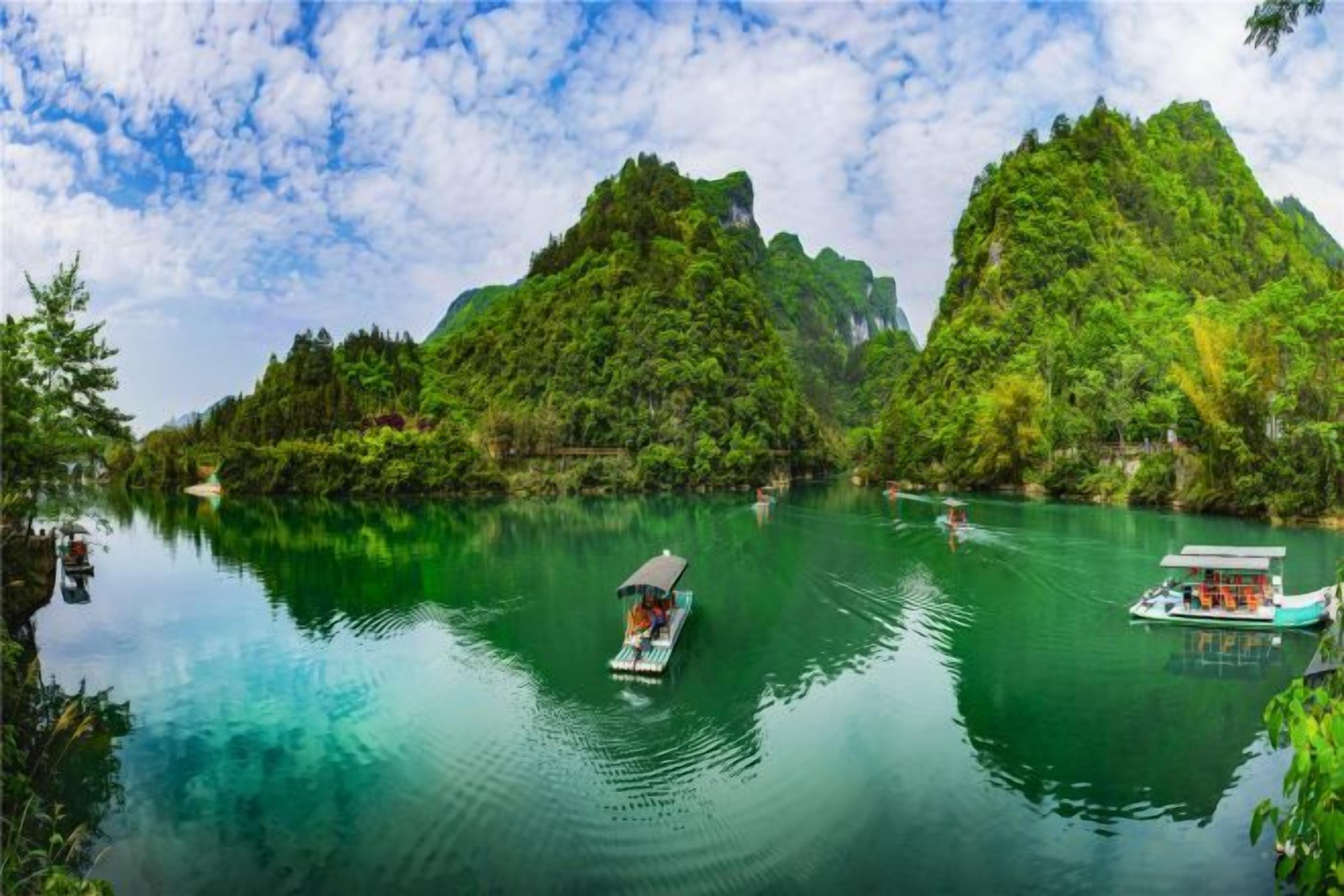A calm river with boats, surrounded by lush green hills.