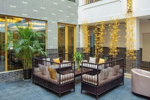 A courtyard with outdoor seating, potted plants, and a modern building facade. - Libo Daqikong Bamboo Garden Boutique Hotel (East Gate Ticket Hall Store of Xiaoqikong Scenic Area) (Libo)