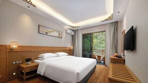A hotel room with a large bed, bedside table, and a TV mounted on the wall. - Libo Daqikong Bamboo Garden Boutique Hotel (East Gate Ticket Hall Store of Xiaoqikong Scenic Area) (Libo)