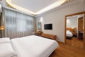 A hotel room with a large bed, a desk, a television, and a mirror.